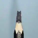 Terrier à poil long - Figurine miniature représentant un chien de type terrier assis, avec pelage long et touffu, oreilles dressées et détails du museau.