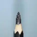 Bouddha en méditation - Sculpture miniature représentant un Bouddha assis en position de méditation, drapé dans une robe, posé sur un socle ornemental à motifs en relief.